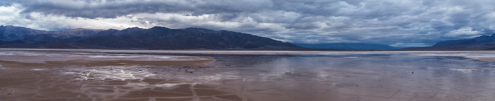 Cracked mud and salt on the valley floor in Death Valley National Park in California can become a reflective pool after rains